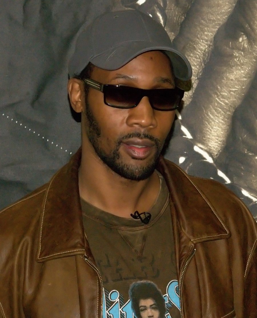 RZA in a gray cap, dark glasses and a brown leather jacket