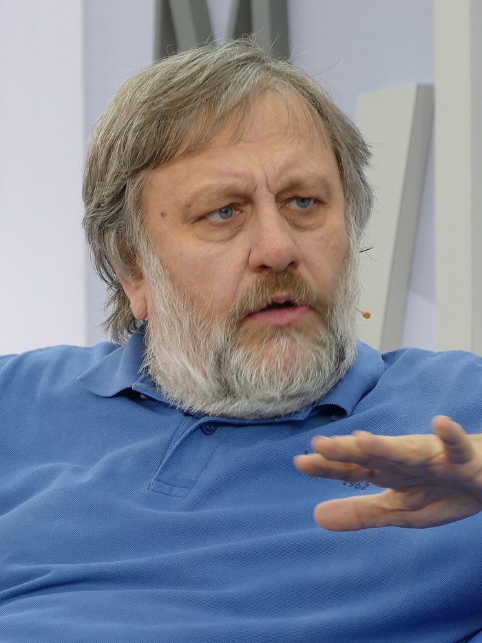 Slavoj Žižek speaking, in a blue shirt, gesturing with one hand